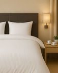 Luxe dekbedovertrekset van katoen-satijn in wit kleur, opgemaakt op een hotelwaardig bed