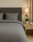 Luxe dekbedovertrekset van katoen-satijn in grijs kleur, opgemaakt op een hotelwaardig bed