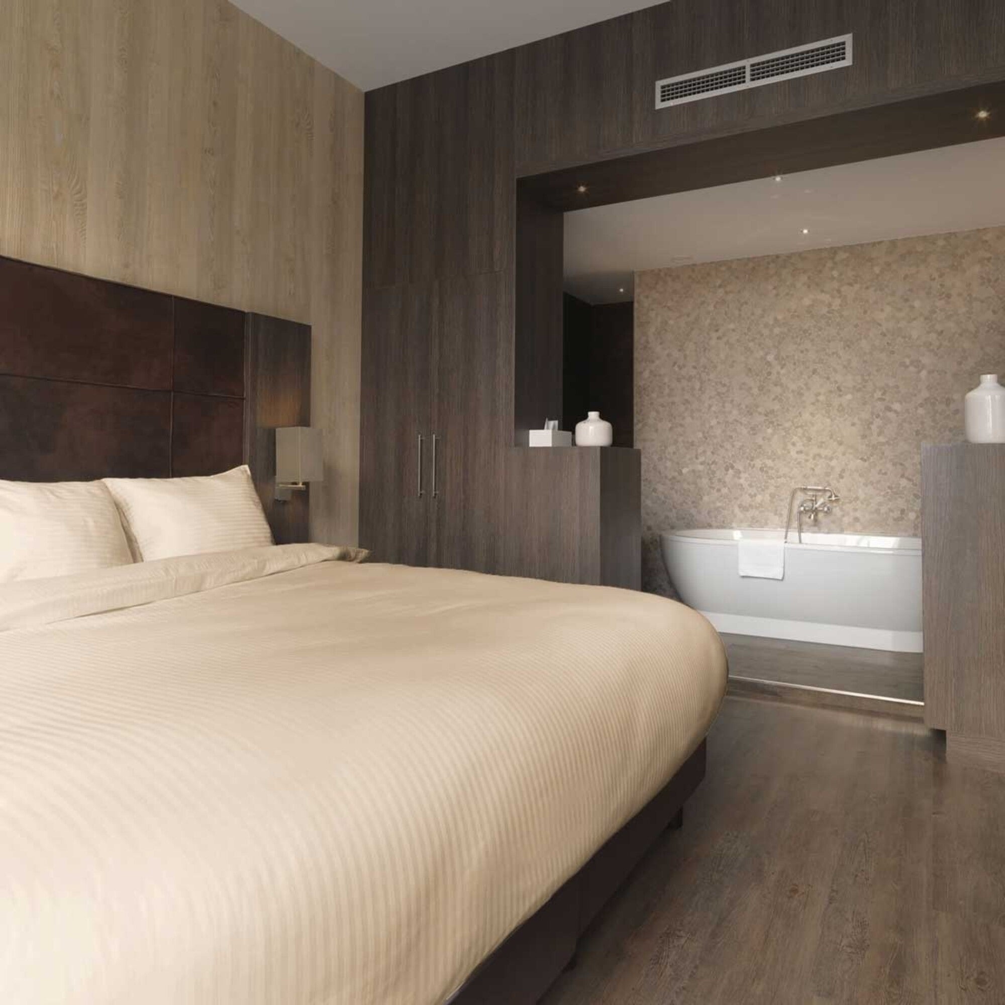 Luxe dekbedovertrekset van katoen-satijn in zand kleur, opgemaakt op een hotelwaardig bed