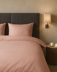 Luxe dekbedovertrekset van katoen-satijn in roze kleur, opgemaakt op een hotelwaardig bed